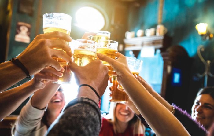 Stock image of a group of people toasting drinks in a bar