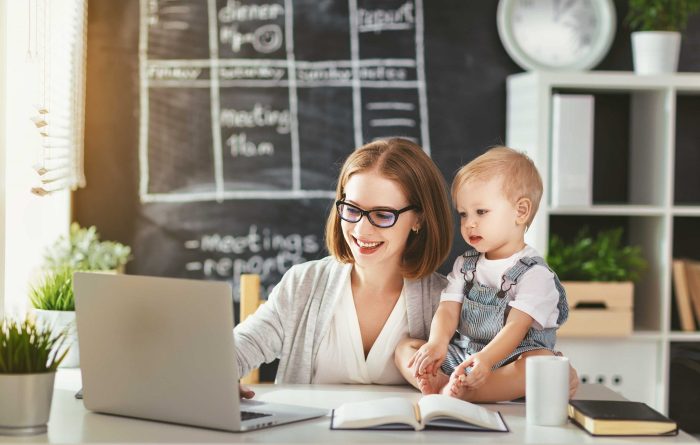 Stock image of a woman working on a laptop with her child