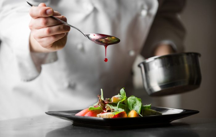 chef pouring sauce on gourmet meal