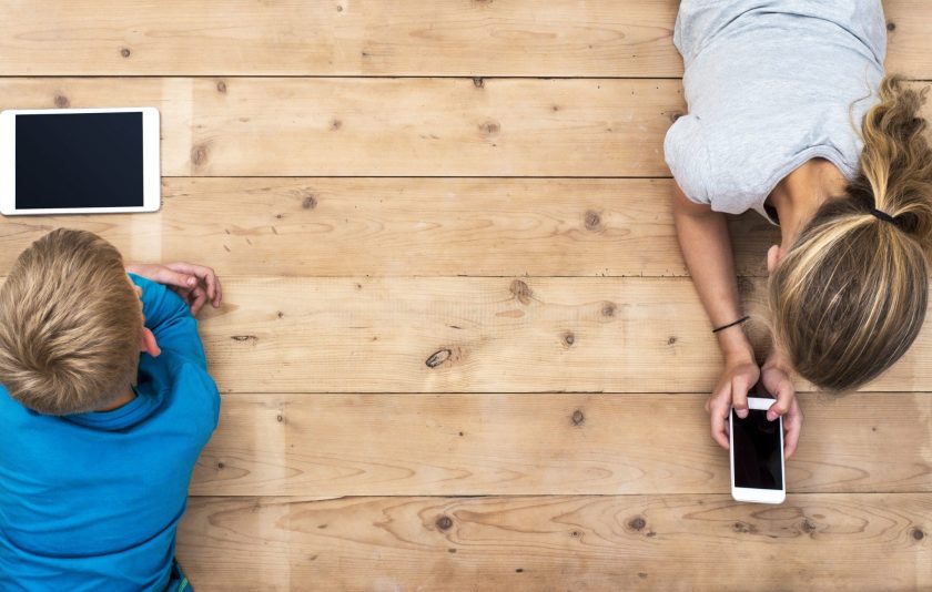 Children's Code: two children lying and using smart phones