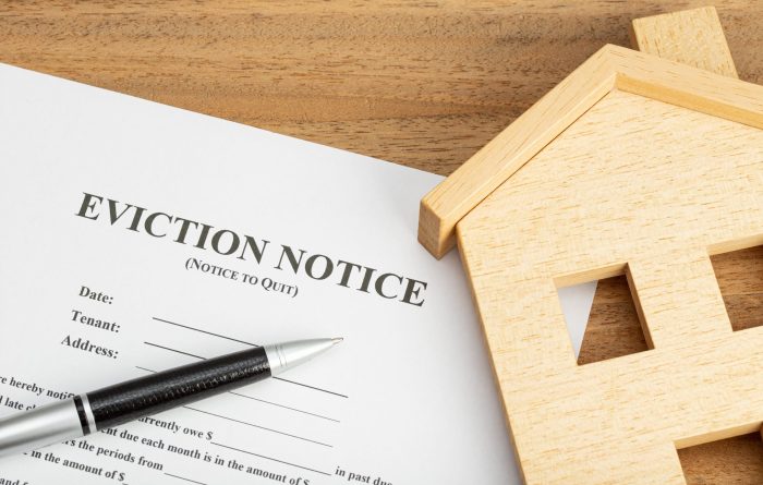 Eviction notice document and toy house on a table