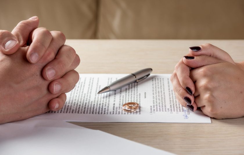 Hands of wife and husband signing divorce papers