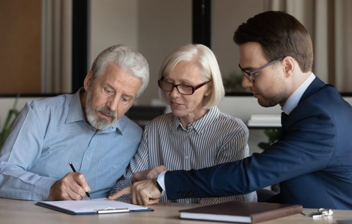 couple looking over documents given to them by a man in a suit.