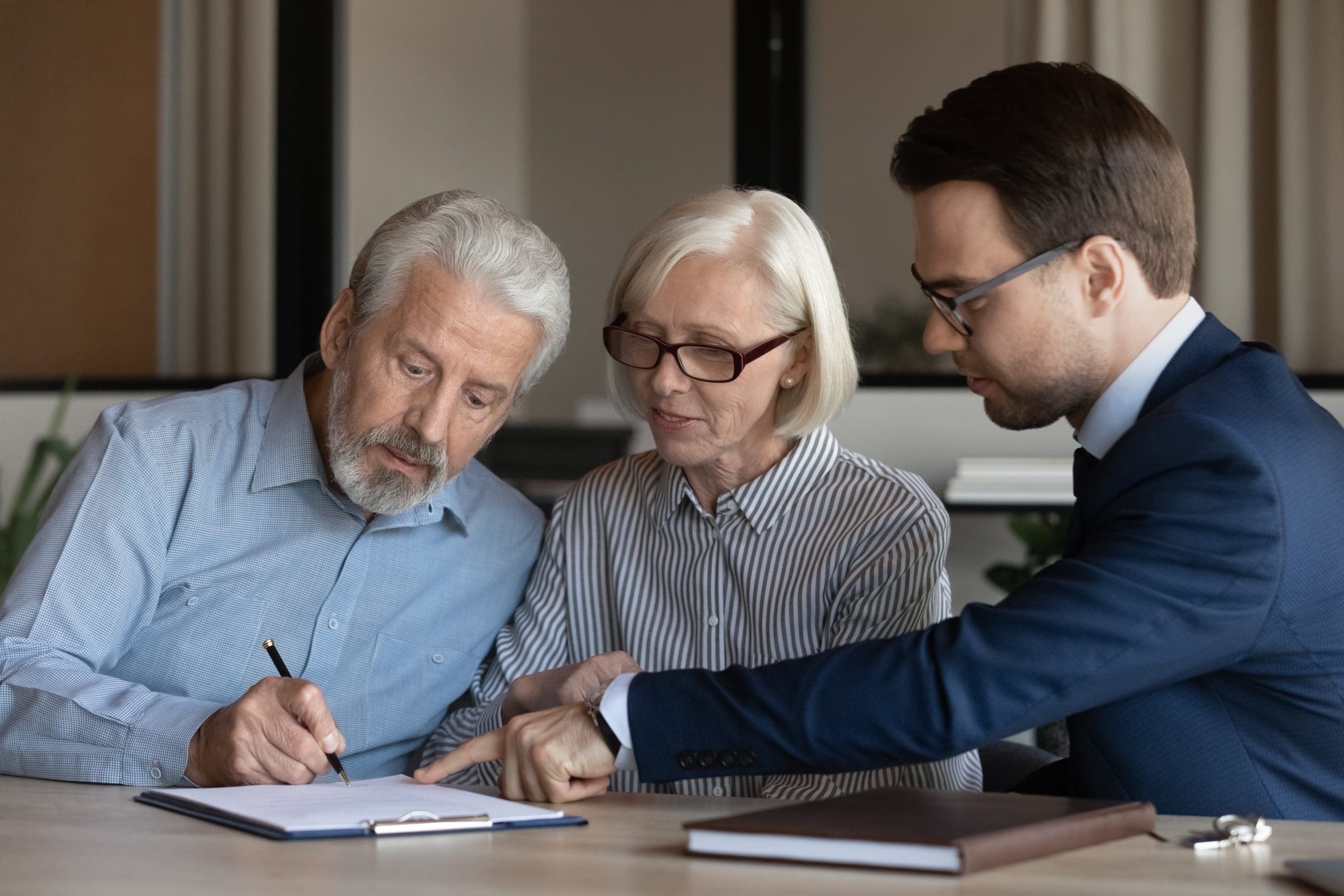 couple looking over documents given to them by a man in a suit.