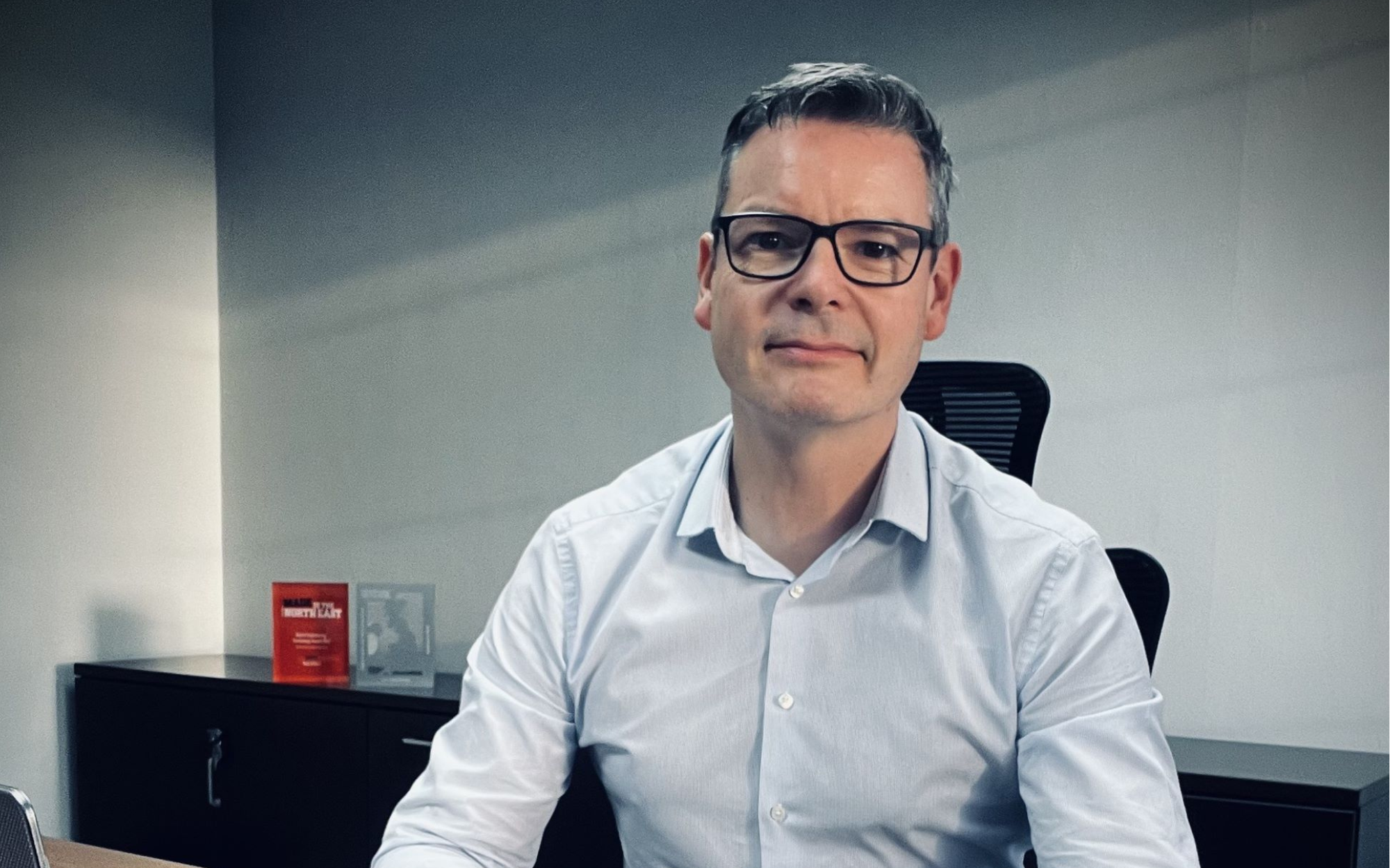 Andrew Hewitson, CEO of Reproflex3 sits at a desk in a blue shirt